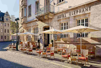 ein Hotelgebäude mit Stühlen und Sonnenschirmen